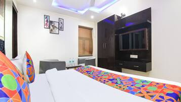A hotel room with a bed, a TV, a wardrobe, a desk, and a window with curtains.