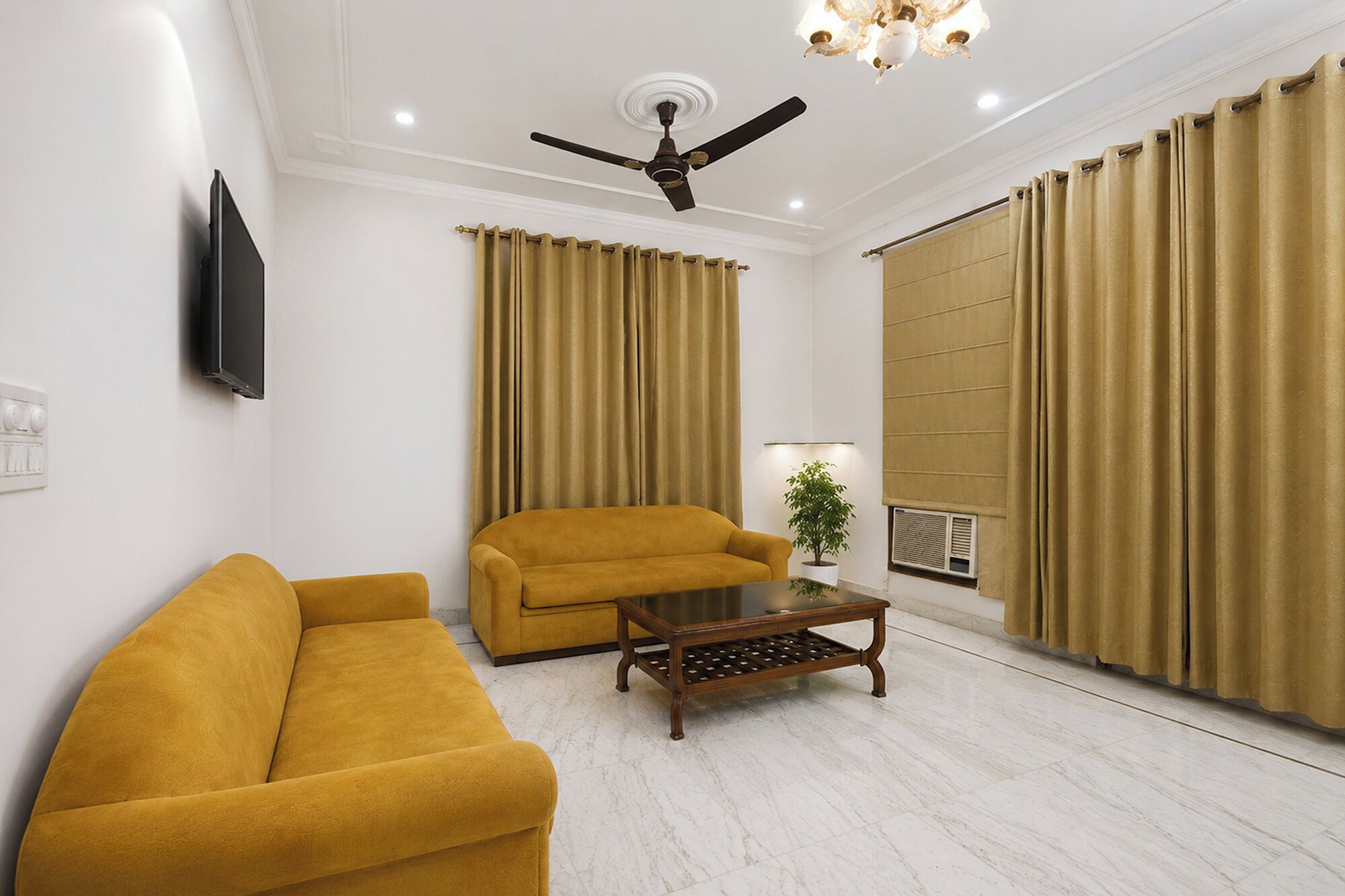 A living room with a sofa, a coffee table, a ceiling fan, and curtains.