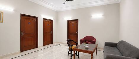 A room with a ceiling fan, a dining table, a sofa, and three wooden doors.