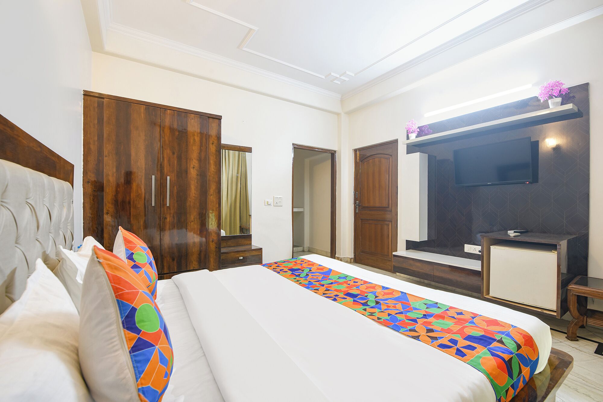 A hotel room with a bed, a TV, a desk, and a wardrobe.