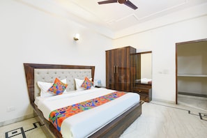 A bedroom with a bed, wardrobe, mirror, ceiling fan, and light fixture. - Fabhotel The Arjun (Gurugram)