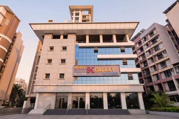 Un hotel llamado 'Hotel SK Galaxy AC Rooms' con un diseño arquitectónico moderno, que presenta una entrada destacada y varios pisos.