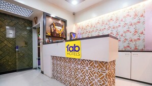 A reception desk with a 'fab hotels' sign, a decorative wall with floral wallpaper, and a patterned partition. - Fabhotel Sk Galaxy (Thane)