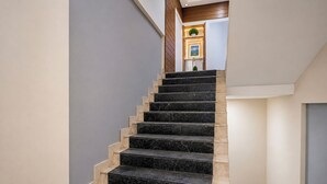 A staircase with alternating black and beige steps leading to a landing with a door and a small plant. - Fabhotel Sk Galaxy (Thane)