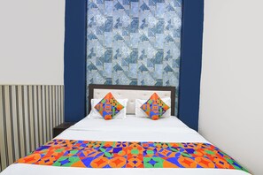 A bed with a geometric-patterned bedspread, two pillows with a similar design, and a wall with a blue and white geometric tile pattern. - Fabhotel Metro Inn I (New Delhi)