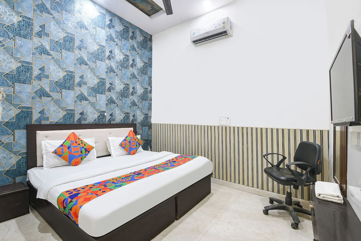 Una habitación de hotel con una cama, una silla, un televisor y un equipo de aire acondicionado.