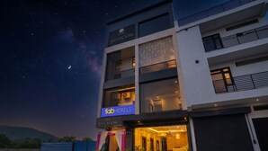 Un hôtel moderne doté d’un balcon, d’une enseigne indiquant « The Ballroom », et surplombant un ciel étoilé.