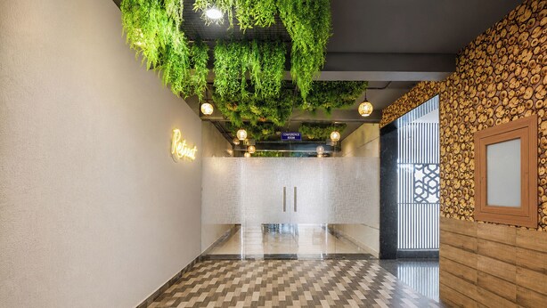 Un couloir doté d’un sol à carreaux, une salle de conférence et un espace d’accueil avec un panneau lumineux au néon.