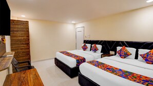 Habitación de hotel con dos camas, un banco de madera, un escritorio y una puerta.