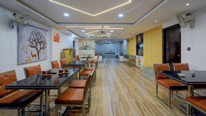 A restaurant with long tables, chairs, and a wooden floor. - Fabhotel Svr Lavish Lounge (Hyderabad)