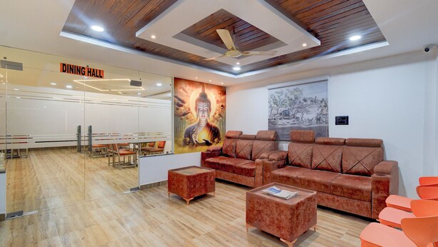 A modern dining hall with a ceiling fan, wooden beams, and a Buddha mural. - Fabhotel Svr Lavish Lounge (Hyderabad)