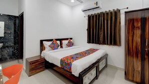 A bedroom with a bed, a ceiling fan, an air conditioning unit, a wooden wardrobe, and a bathroom with a marble wall. - Fabhotel Svr Lavish Lounge (Hyderabad)