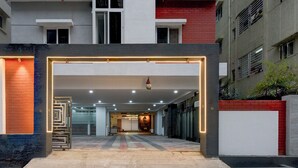 A modern building entrance with a glass door, a visible staircase, and a red brick wall. - Fabhotel Svr Lavish Lounge (Hyderabad)