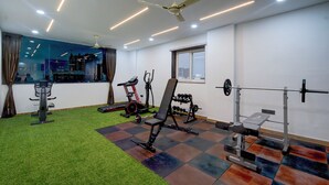 A gym with exercise equipment, a ceiling fan, and a window. - Fabhotel Svr Lavish Lounge (Hyderabad)