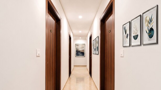 Um corredor com portas de madeira, piso de mármore e obras de arte emolduradas nas paredes.