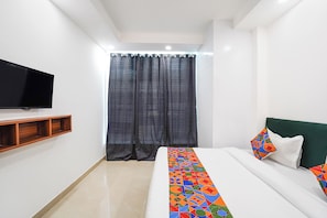 A bedroom with a bed, a TV mounted on the wall, a curtain, and a shelf. - FabHotel Ostan Stayz 15 - Noida Sector-15 (Noida)