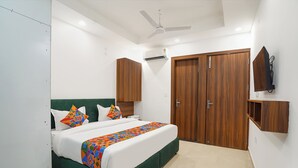 Quarto com cama, ventoinha no teto, ar condicionado, armários de madeira e televisão na parede.