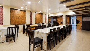 A spacious restaurant with high ceilings, multiple ceiling fans, and a long marble bar. - FabHotel Prime The City Park (Hyderabad)