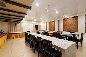 A dining area with multiple tables and chairs, ceiling fans, and a patterned wall. - Fabhotel Prime The City Park (Hyderabad)