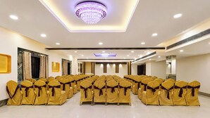 A conference room with rows of chairs, a chandelier, and a modern ceiling design. - FabHotel Prime The City Park (Hyderabad)