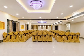 A conference room with rows of chairs, a chandelier, and a modern ceiling design.