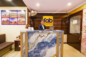 A hotel reception desk with a laptop, a sign for 'fab hotels,' and a poster of Hyderabad sites. - Fabhotel Prime The City Park (Hyderabad)