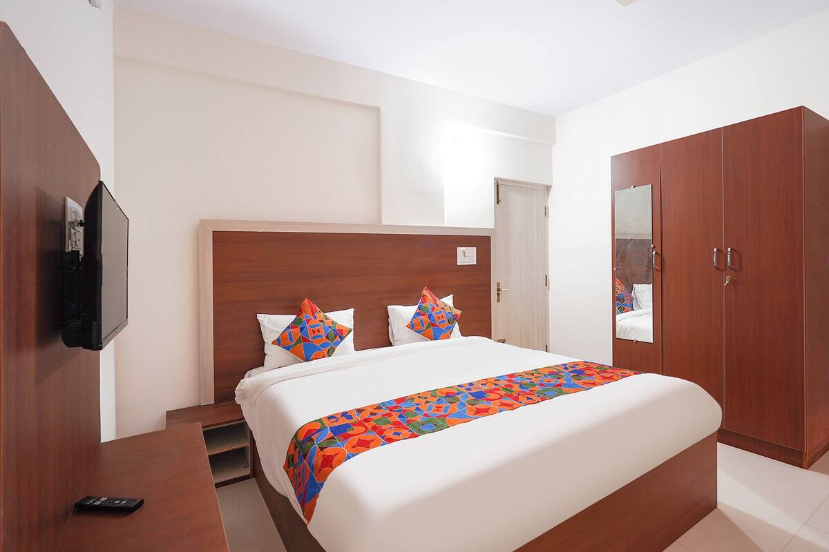 A hotel room with a bed, a TV, a wardrobe, and a mirror.