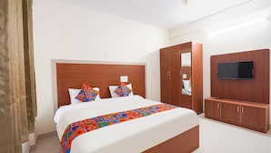 Ein Hotelzimmer mit einem großen Bett, einem Holzkopfteil, einem Wandfernseher und einem Kleiderschrank.