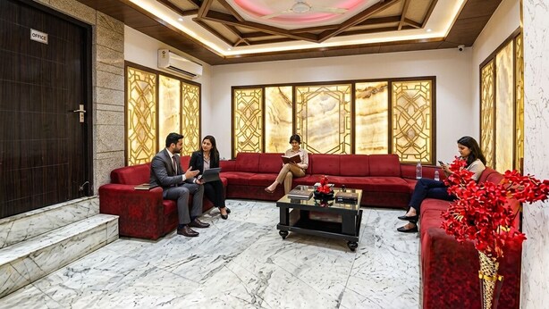 A lobby with a marble floor, red sofas, a coffee table, and decorative panels. - Fabhotel Perfectionist (New Delhi)