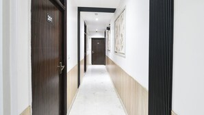 A hallway with doors marked 201 and 203, a light-colored floor, and a wall with a vertical black stripe. - Fabhotel Perfectionist (New Delhi)