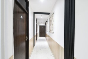A hallway with doors marked 201 and 203, a light-colored floor, and a wall with a vertical black stripe. - Fabhotel Perfectionist (New Delhi)