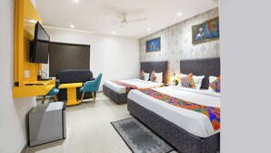 A hotel room with a bed, a desk, a chair, a television, and a ceiling fan. - Fabhotel Perfectionist (New Delhi)