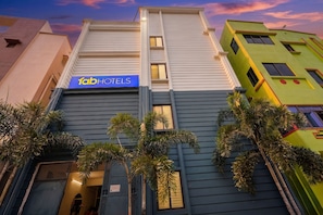 Un hotel con un letrero azul, diseño moderno y palmeras al frente.