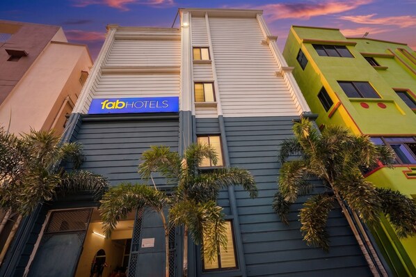 Un hôtel avec une enseigne bleue, un design moderne et des palmiers à l’avant.