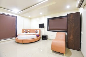 A bedroom with a bed, a chair, a TV, and a wardrobe. - Fabhotel Nirvana (Pune)