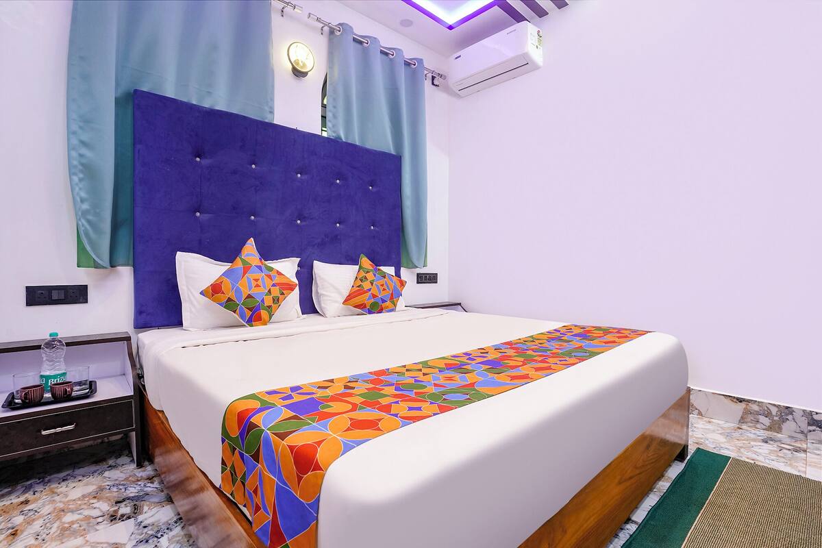 Een hotelkamer met een bed, een nachtkastje, een waterfles en een stopcontact.