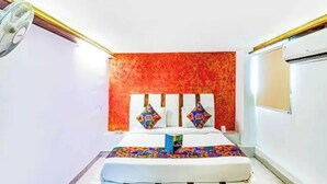 Un dormitorio con una cama, un ventilador de pared y una ventana.