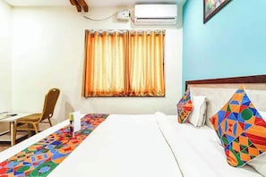 A hotel room with a bed, a chair, a table, and an air conditioning unit. - FabHotel Vaishnavi Grand - Near Secunderabad Railway Station (Hyderabad)