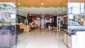 Un interior moderno con entrada de vidrio, techo de madera y un área de descanso con sofás.
