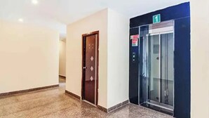 Un pasillo con una puerta de madera y un ascensor.
