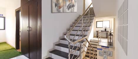 A staircase with metal railings, a reception counter, and a door with a green mat.
