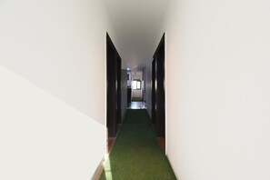 A narrow hallway with a green carpet, white walls, and a door at the end. - Fabhotel Akshay Inn (Pune)