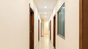 A corridor with wooden doors and a framed picture on the wall. - FabHotel Grand Villa (Indore)