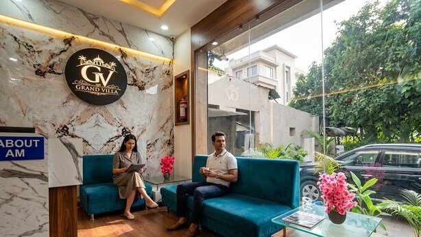 A hotel reception area with a marble wall, a sign reading 'Grand Villa,' and a reception desk. - FabHotel Grand Villa (Indore)