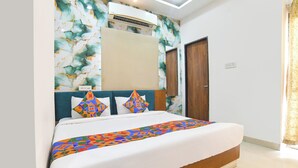 A bedroom with a bed, a headboard, a wall-mounted air conditioner, and a door. - FabHotel Grand Villa (Indore)