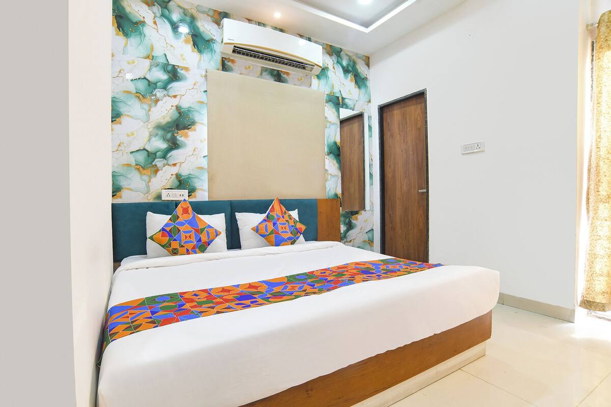 Ein Schlafzimmer mit Bett, Kopfteil, Wandklimaanlage und einer Tür.