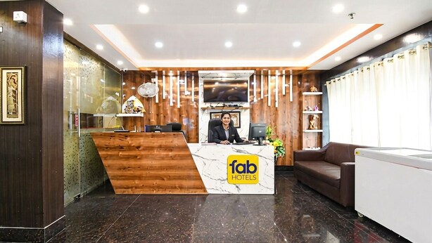 A reception desk with a logo, a TV, a sofa, and a refrigerator. - FabHotel Leechi Lodging & Fooding - Nr. AIIMS (Kalyani)