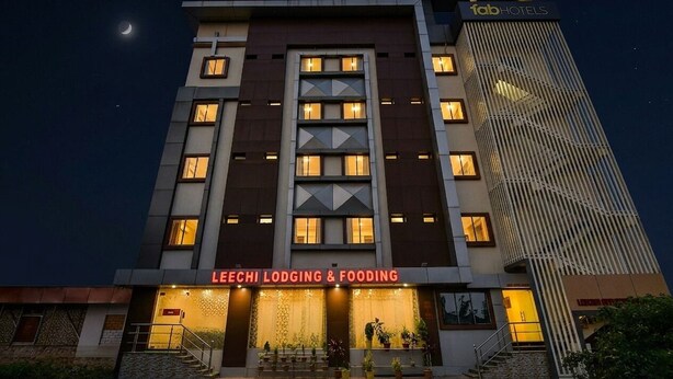 Un edificio de varios pisos con un letrero llamativo que dice 'LEECHI LODGING & FOODING' al nivel de la calle.