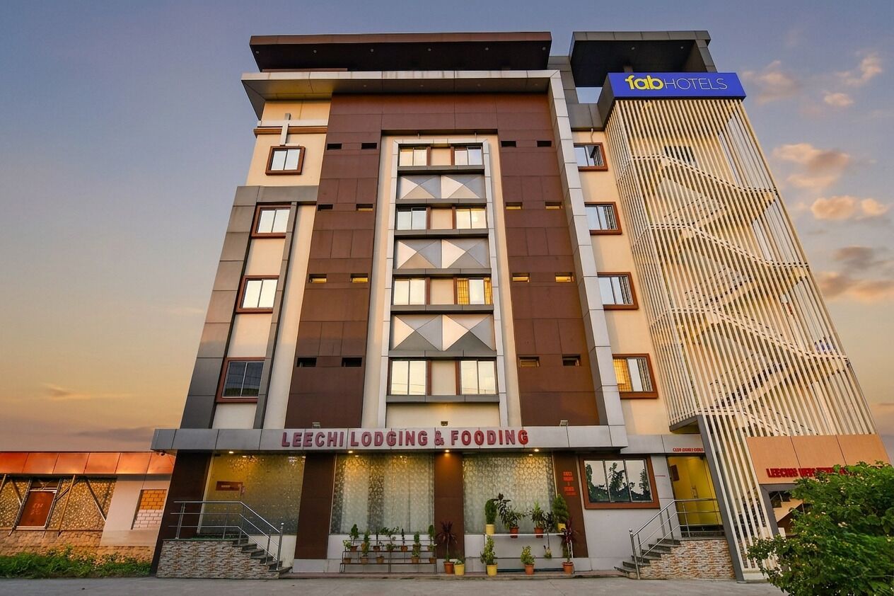 A multi-story hotel with a modern facade, featuring a prominent sign for 'LEECHI LODGING & FOODING' and a separate sign for 'fabHOTELS' on the top right.