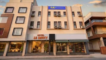 A multi-story hotel with a modern facade, air conditioning units, and a visible restaurant on the ground floor.